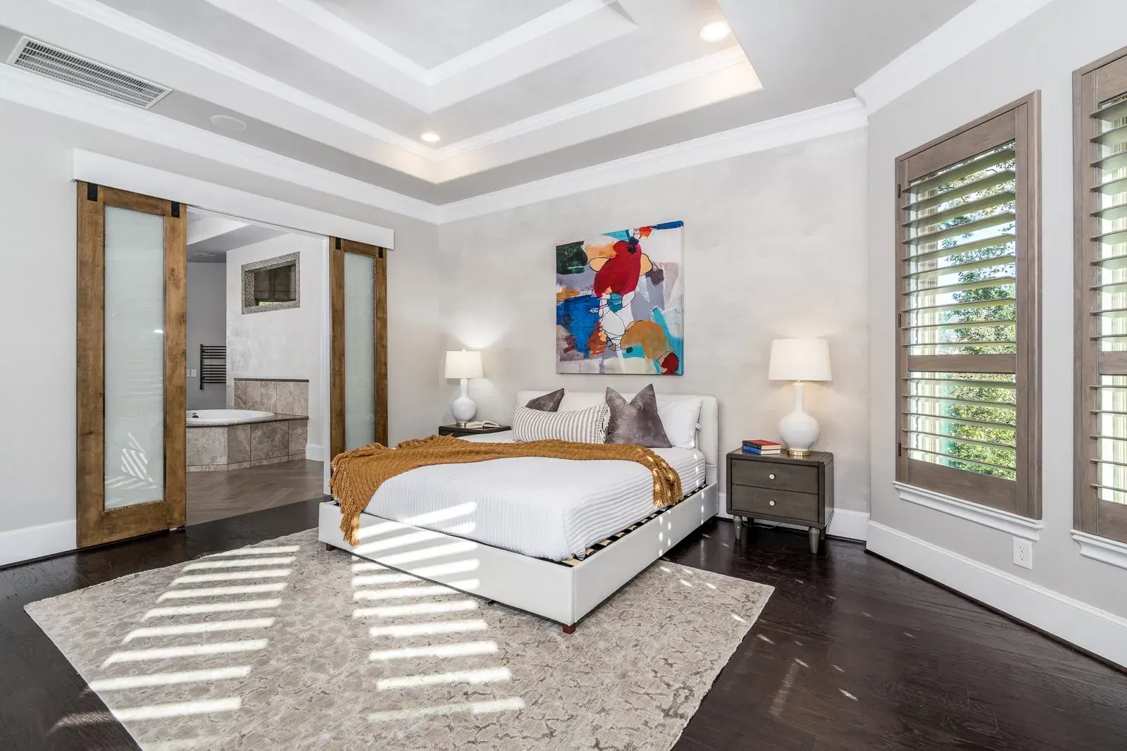 Primary bedroom with plantation shutters, art, and a sitting chair