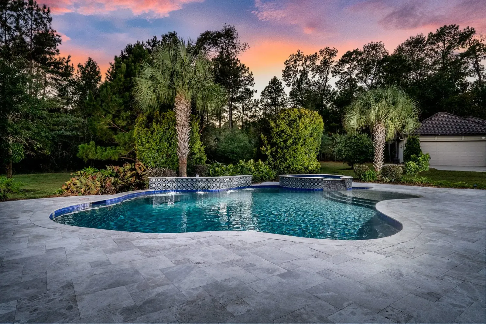 Freeform pool with spa and palms under a pink twilight sky