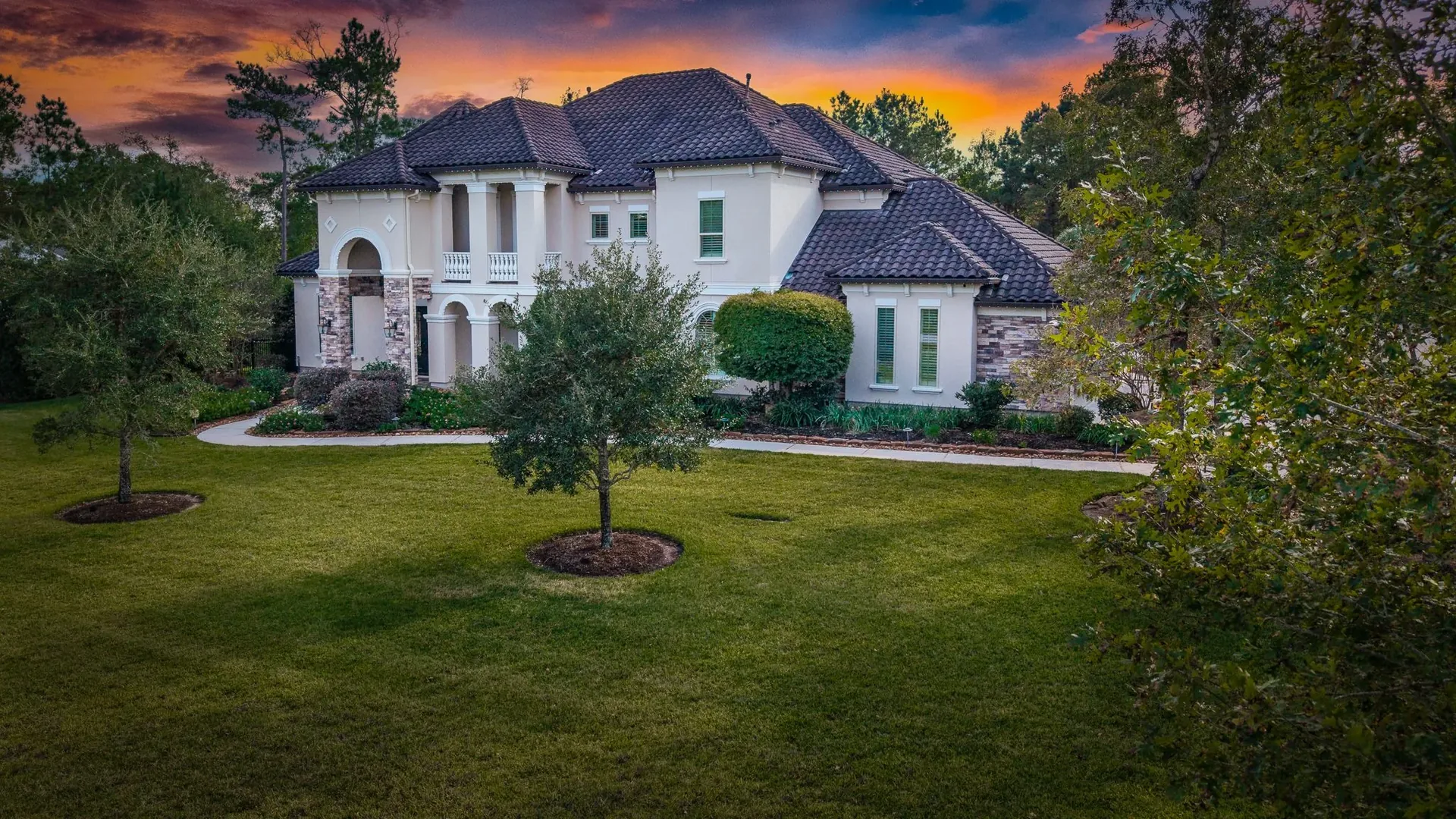 Two-story Mediterranean estate at twilight with a saturated orange sky, Cypress, Texas