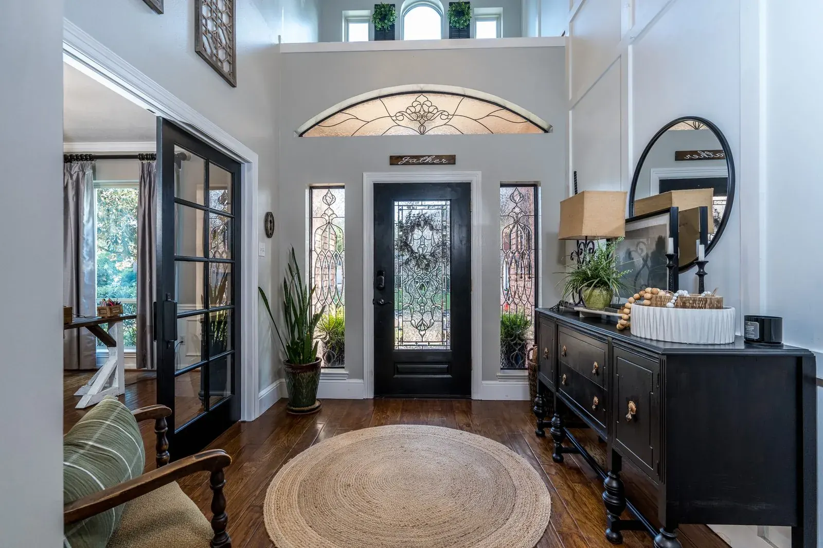 Two-story foyer with leaded-glass front door, dark millwork, and hardwood floors